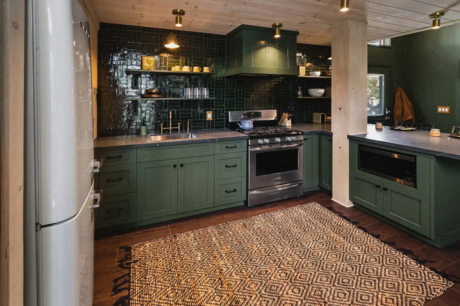Juniper's kitchen features counter-to-ceiling tile, a gas stove, Smeg fridge, microwave, and all the utensils you need to enjoy meals in the cabin.
