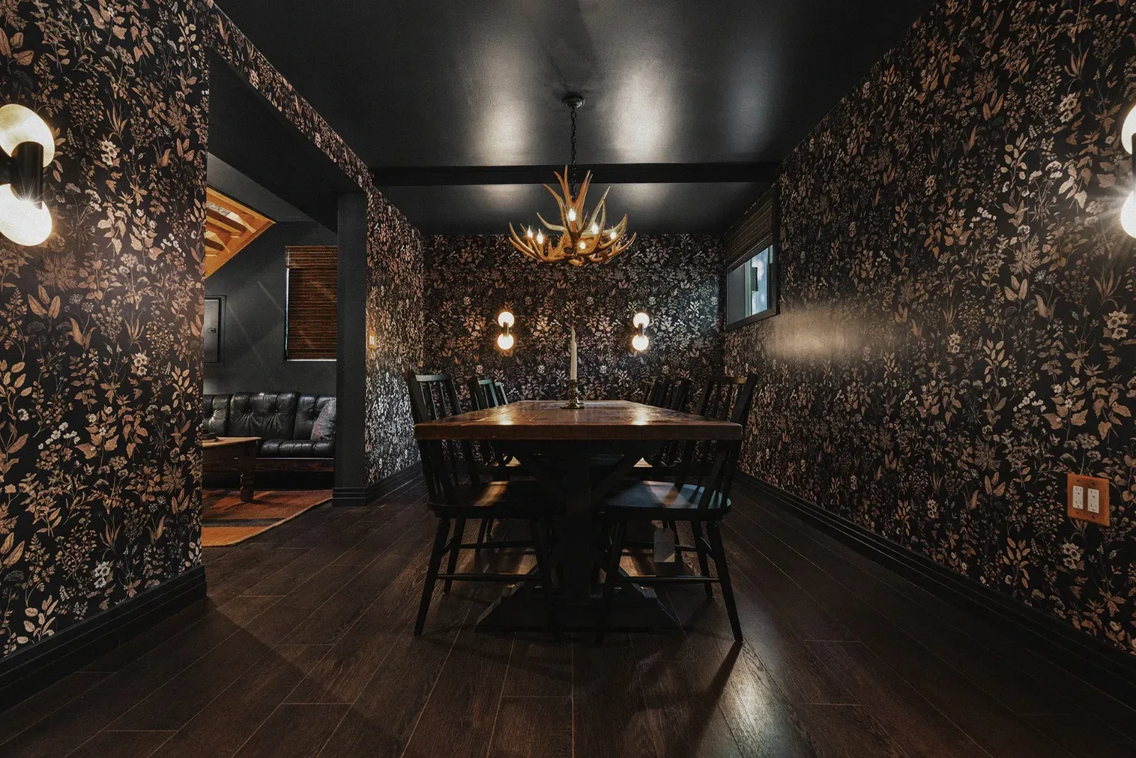 Enjoy the expansive dining area with your guests while you are immersed in the modern lodge decor, including an antler chandelier and black & tan wallpaper.